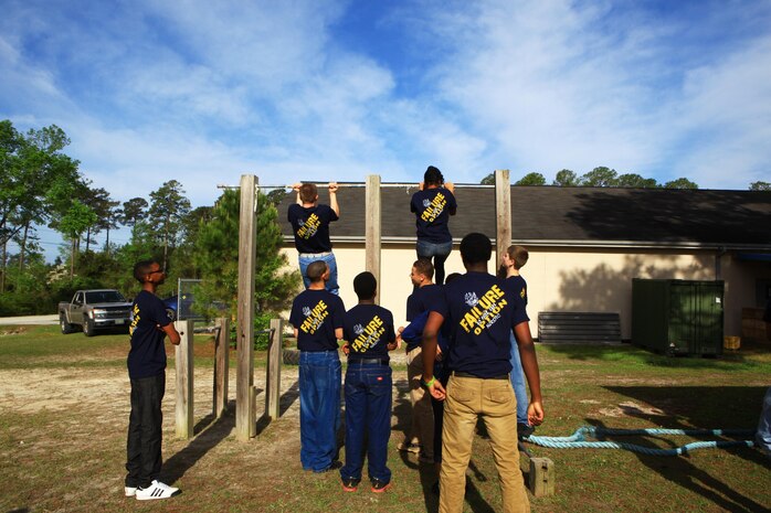 Naval JROTC students from Northeast Guilford High School attempt pull-ups outside of the Basic Skills Training School aboard Camp Lejeune, N.C., April 18, 2013. The students traveled from Greensboro, N.C., to tour the base and shot at the indoor simulated marksmanship trainer. 