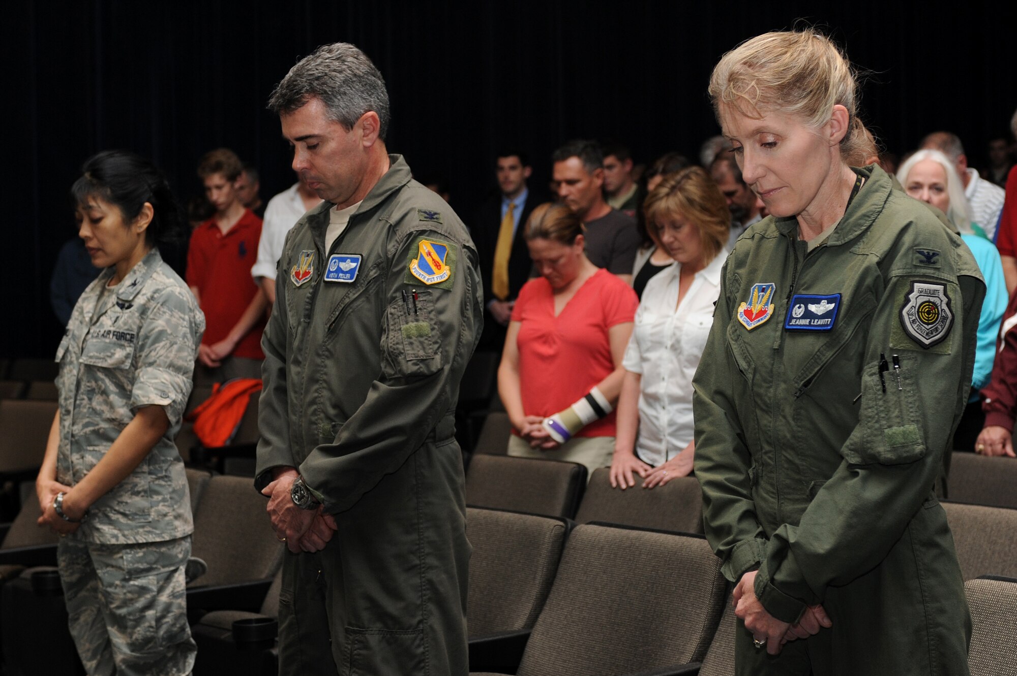 U.S. Air Force Col. Leslie Claravall, 4th Medical Group commander, Col. Kevin Fesler, 414th Fighter Group commander, and Col. Jeannie Leavitt, 4th Fighter Wing commander, join in the invocation during the Retreat Ceremony and Roll Call at the base theatre on Seymour Johnson Air Force Base, N.C., April 12, 2013. The 4th FW held the ceremony to commemorate the F-15E Strike Eagle and the 14 aircrew members who made the ultimate sacrifice while protecting the freedoms. (U.S. Air Force photo by Airman 1st Class John Nieves Camacho/Released)