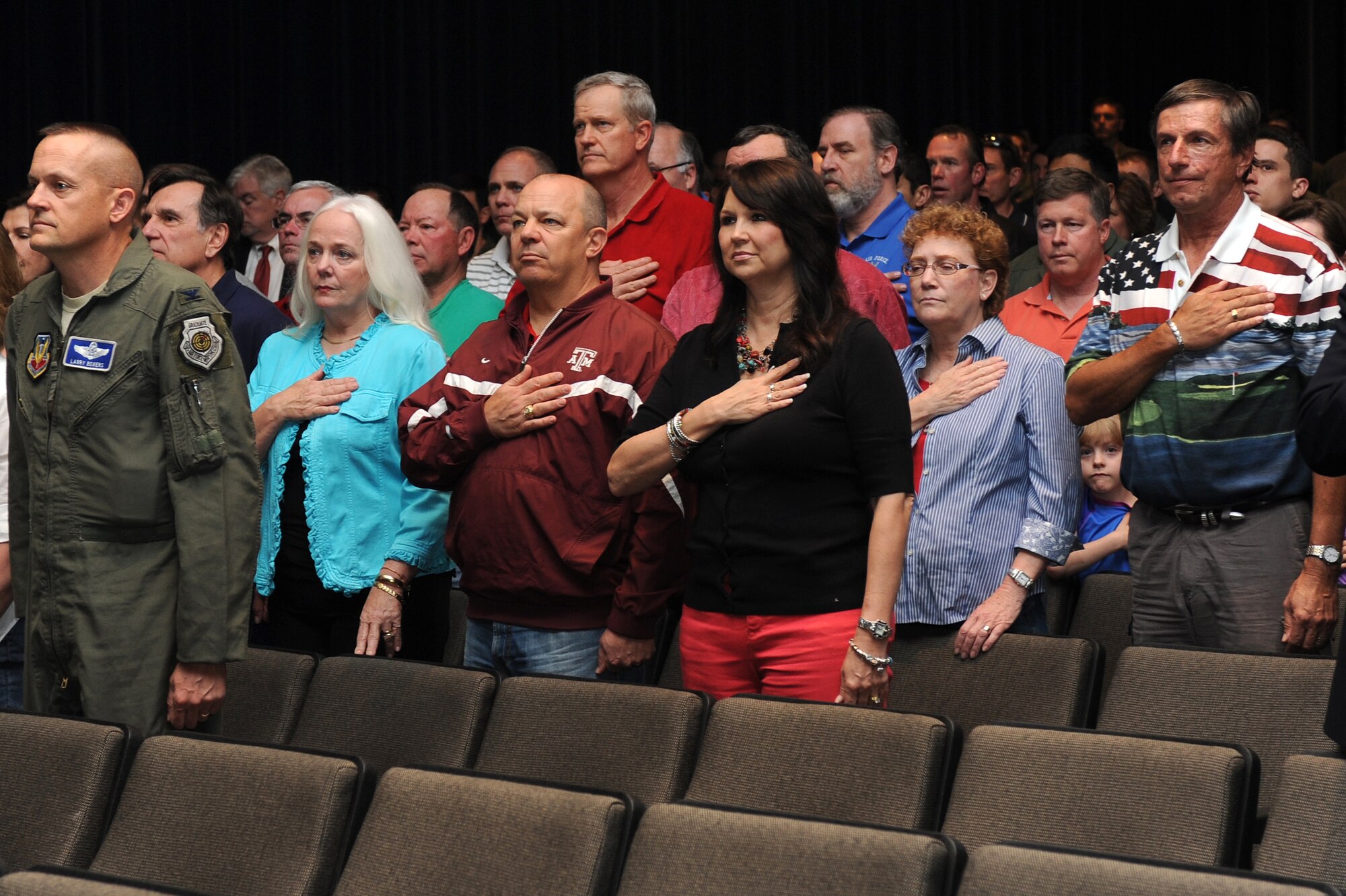 Patrons of the Retreat Ceremony and Roll Call, for the F-15E Strike Eagle 25th Anniversary, render courtesies during the national anthem at the base theatre on Seymour Johnson Air Force Base, N.C., April 12, 2013. Airmen, past and present, across the globe along with members of Team Seymour gathered to pay respect to the 14 aircrew members who gave their lives protecting freedoms. (U.S. Air Force photo by Airman 1st Class John Nieves Camacho/Released)