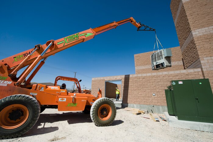 Construction workers lower a chiller into the F-35A Lightning II Maintenance Hangar near the flight line April 15, 2013, at Nellis Air Force Base, Nev. The hangar will be used for maintenance and repairs on the F-35A Lightning II. (U.S. Air Force photo by Airman 1st Class Christopher Tam)