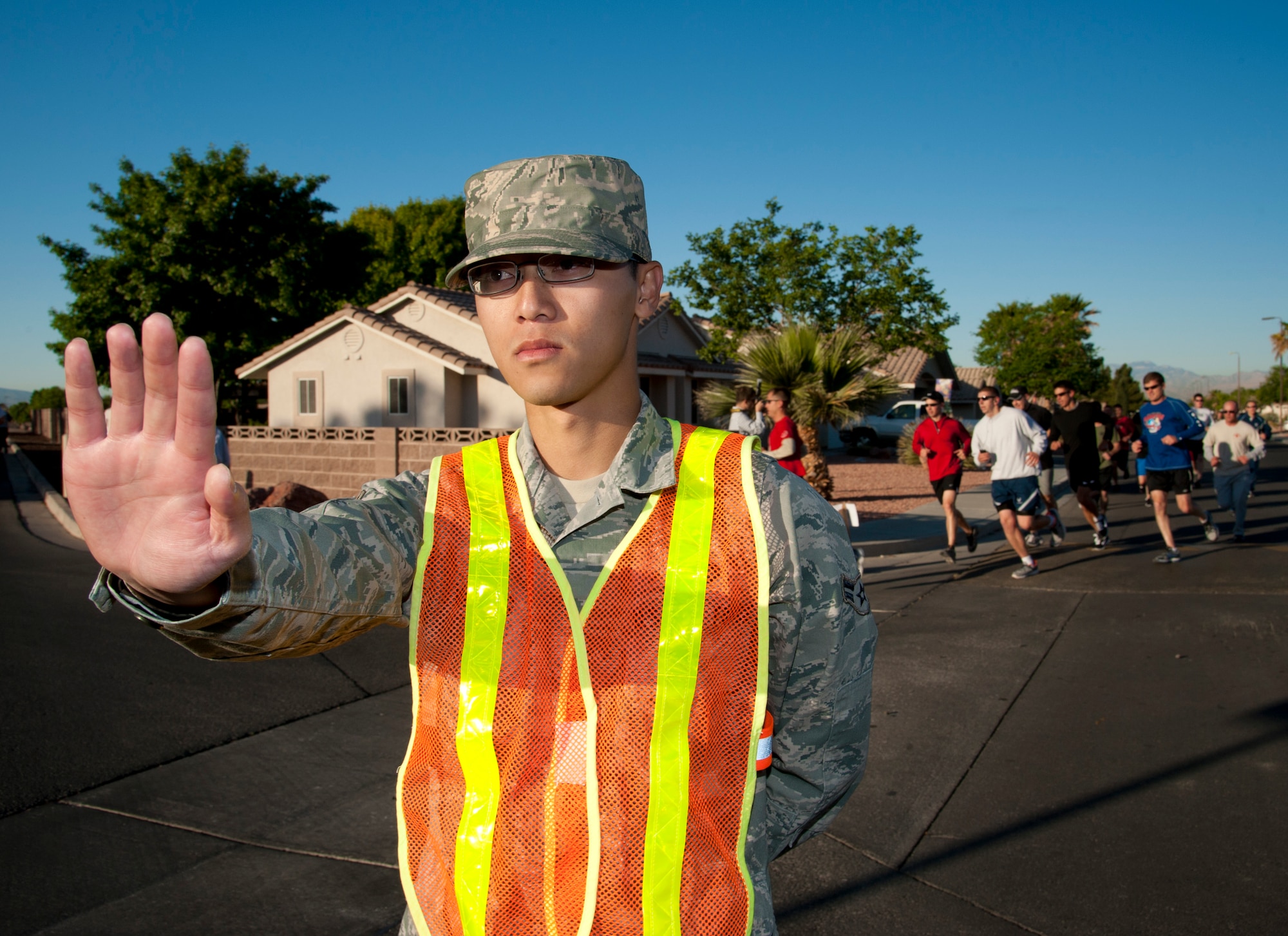 Airman 1st Class Hoang Vuong, 99th Comptroller Squadron finance technician, stops traffic for runners participating in the Survive and Thrive 5-kilometer April 19, 2013, at Nellis Air Force Base, Nev. The event was open to active-duty service members, their family members, and civilian employees. (U.S. Air Force photo by Master Sgt. Jason W. Edwards)