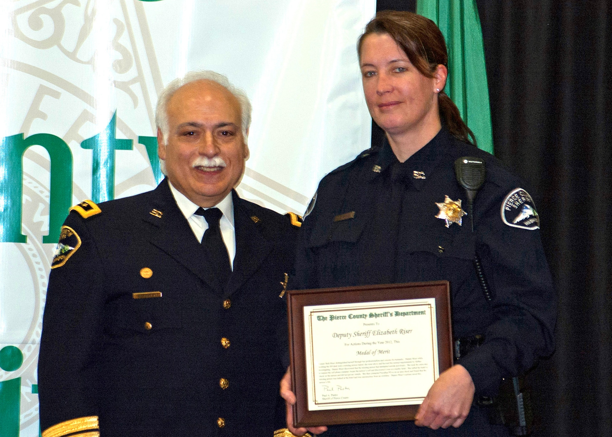 Senior Master Sgt. Liz Riser (right) 86th Aerial Port Squadron first sergeant, accepts her Medal of Merit Award from Sheriff Paul Pastor, Pierce County Sheriff’s Department, Wash., during the department’s Annual Awards Banquet in March 2013. Riser, a sheriff’s deputy earned the award for her selfless acts in helping locate and save a missing person’s life back in September 2012. (Courtesy photo)