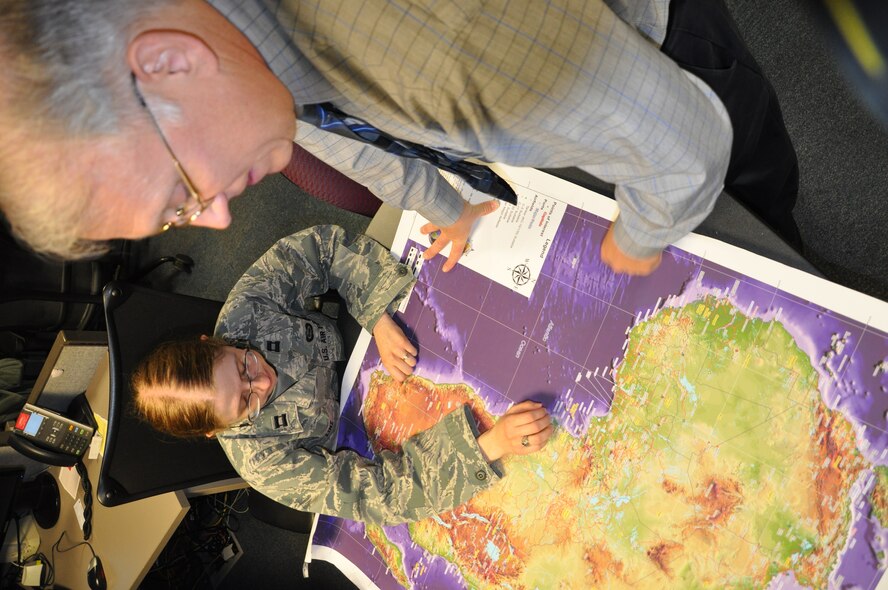 Capt. Jennifer Linz, AMC Air Intelligence Squadron’s Africa Command/European Command (AFRICOM/EUCOM) Branch chief, discusses information with Bill Farrell, the squadron’s senior civilian analyst, in preparation for an intelligence briefing. Air Intelligence Squadron’s Africa Command/European Command (AFRICOM/EUCOM) Branch researched and provided intelligence analysis for Mobility Air Forces supporting the French intervention in Mali. (U.S. Air Force photo/Ed Shannon)