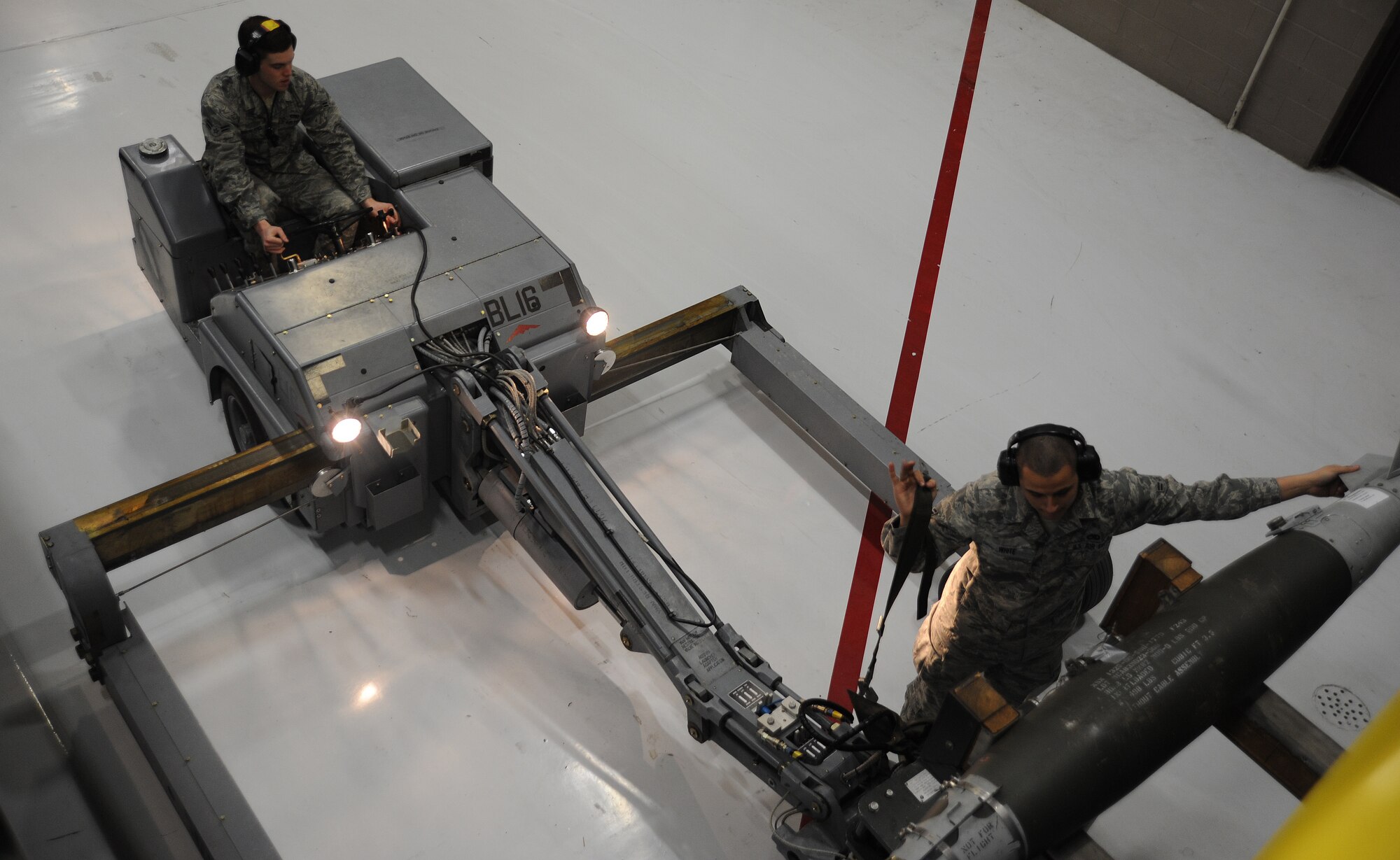 Airman 1st Class Jason White (right), 13th Aircraft Maintenance Unit weapons loader, helps guide Airman 1st Class Justin Sutherland, 13th AMU weapons loader as Sutherland attempts to grab a munition during a weapons load competition at Whiteman Air Force Base, Mo., April 12, 2013. In addition to the hands-on competition, competitors also took a written test and were evaluated on their adherence to dress and appearance standards. (U.S. Air Force photo by Staff Sgt. Nick Wilson/Released)