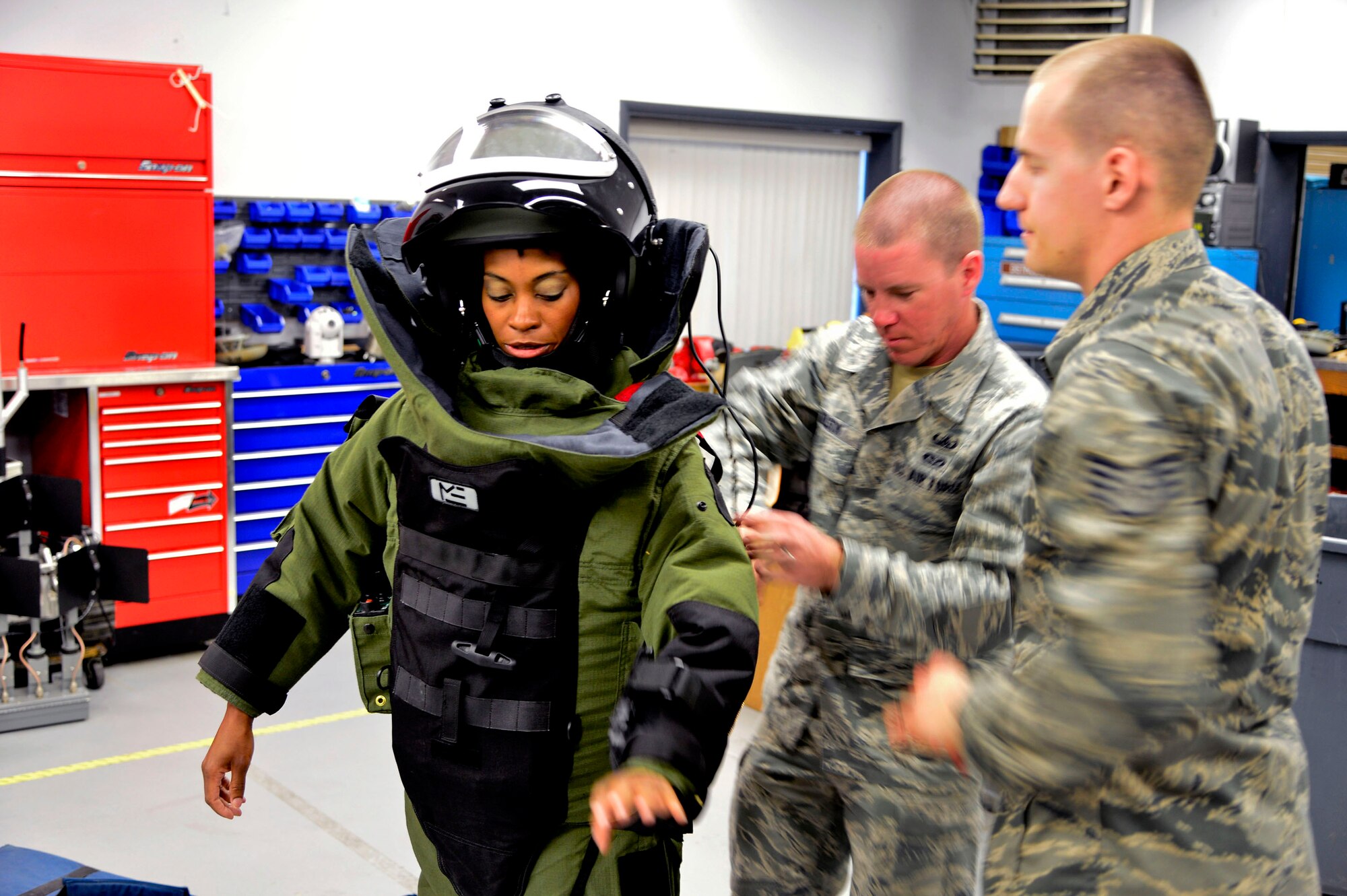 Senior Airman John Nelson,center, and Staff Sgt. John Nelson, from the 436th Civil Engineer Squadron Explosive Ordnance Disposal Flight, demonstrates the EOD 9 Bomb Suit to news reporter Karen Campbell, from Dover TV station WBOC Channel 16, at Dover Air Force Base, Del.,  April 16, 2013. The Media Day was an opportunity for media representatives to get a closer look at and a better understanding of Dover AFB's EOD Airmen and mission. (U.S. Air Force photo/David S. Tucker)
