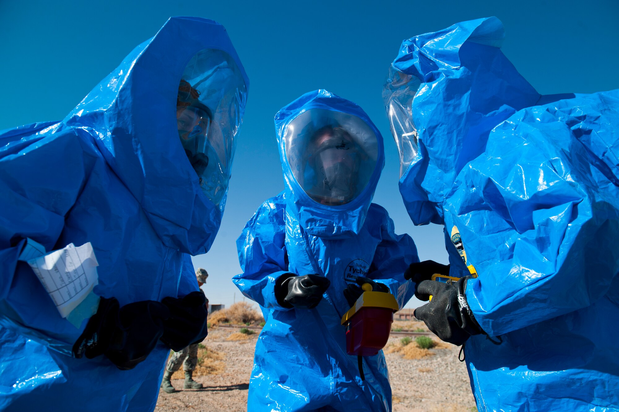 Airman 1st Class Lucas Montoya and Airman 1st Class Peyton Oesterrech, both 49th Civil Engineer Squadron bioenvironmental engineers, and Staff Sgt. Amber Green, 49th Civil Engineer Squadron emergency management, huddle together to decide how they will approach a hazmat training scenario at Holloman Air Force Base, N.M., April 18. Airmen in bioenvironmental and emergency management undergo integrated base emergency response capability training to keep their skills sharp at all times. (U.S. Air Force photo by Airman 1st Class Daniel E. Liddicoet/Released)