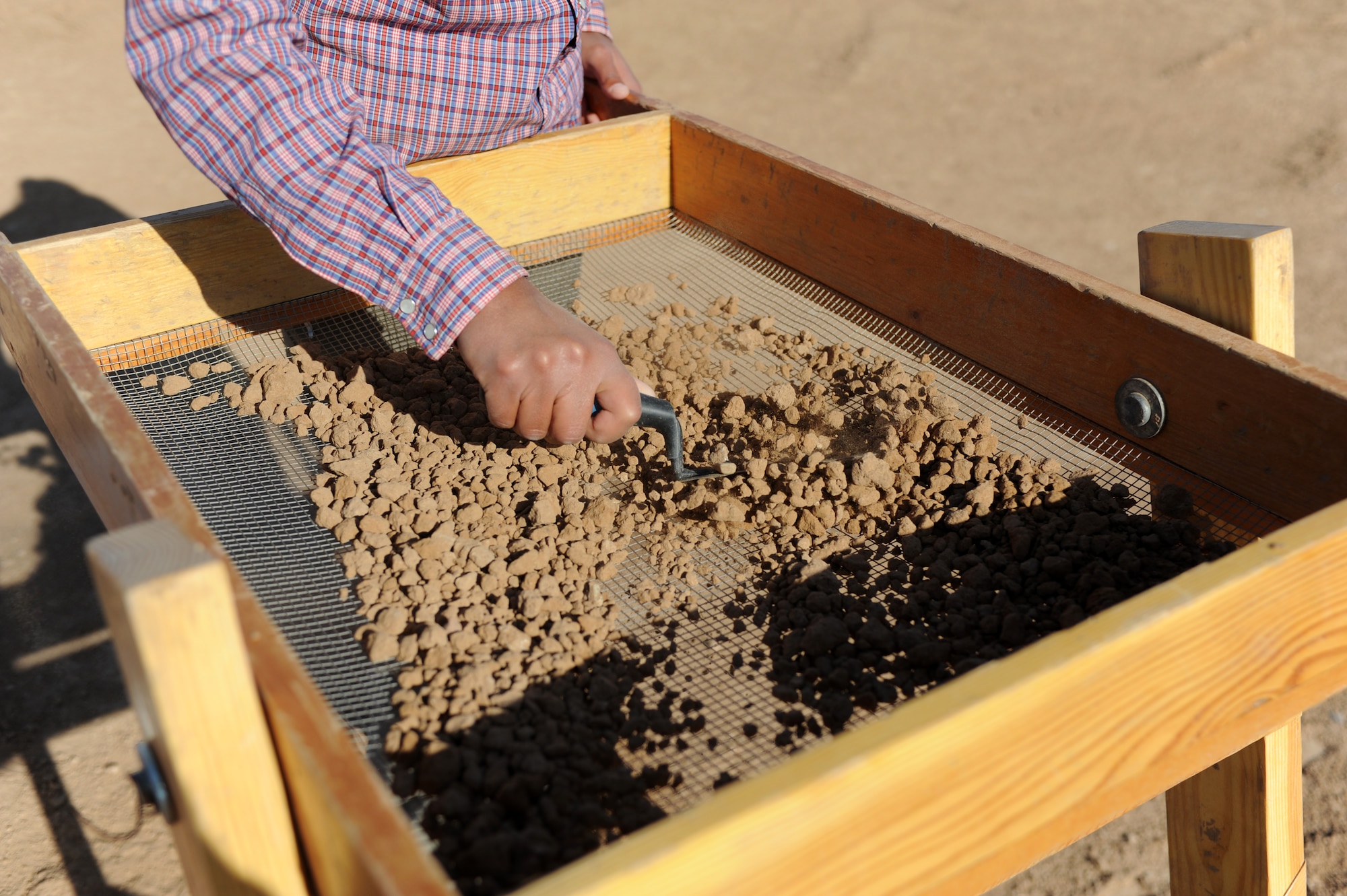 Rachelle Robinson, archaeological field technician, screens dirt for artifacts at Archaeological Site 419 April 12. Dirt from the digging is screened and scanned to find small artifacts that may be missed by the human eye. (U.S. Air Force photo/Airman 1st Class Devante Williams)