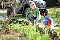 Melody McMahon, a volunteer and master gardener, cleans out one of the flower beds in front of the Warrior and Family Support Center.