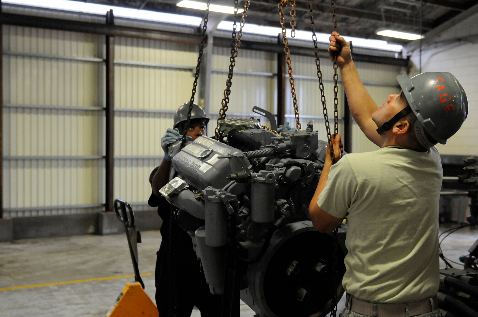U.S. Air Force Air Force Senior Airman Dewight Newberry, 18th Equipment Maintenance Squadron Aerospace Ground Equipment mechanic, and Staff Sgt. Jose Mendez, 1st Maintenance Squadron AGE mechanic, install an engine into a hydraulic test stand on Kadena Air Base, Japan, April 10, 2013. Mendez deployed to Kadena from Langley Air Force Base, Va., to support the F-22 Raptor squadron and worked with 18th EMS AGE Airmen daily to ensure equipment readiness. (U.S. Air Force photo by Staff Sgt. Rachelle C. Coleman/Released)