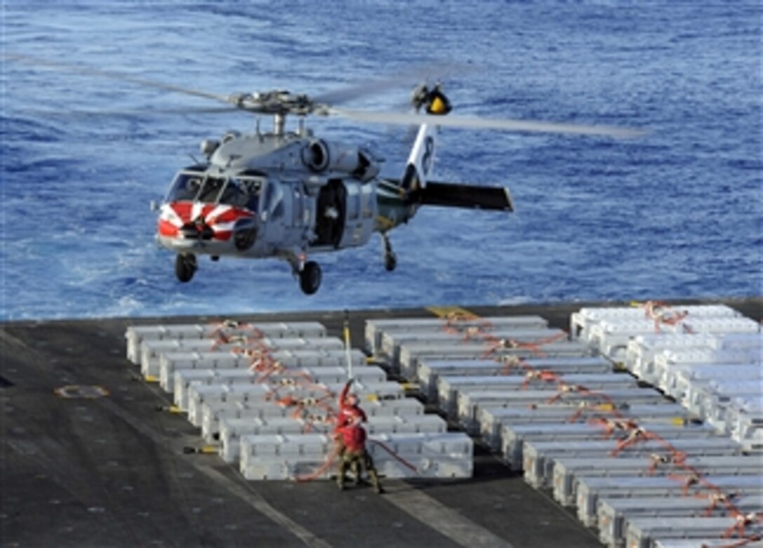 U.S. Navy sailors are poised to attach a sling to an approaching MH-60S Sea Hawk helicopter on the flight deck of the aircraft carrier USS John C. Stennis (CVN 74) during a weapons transfer as the ship operates in the Pacific Ocean on April 18, 2013.  The Stennis is deployed to the 7th Fleet area of responsibility to conduct maritime security operations and theater security cooperation efforts.  