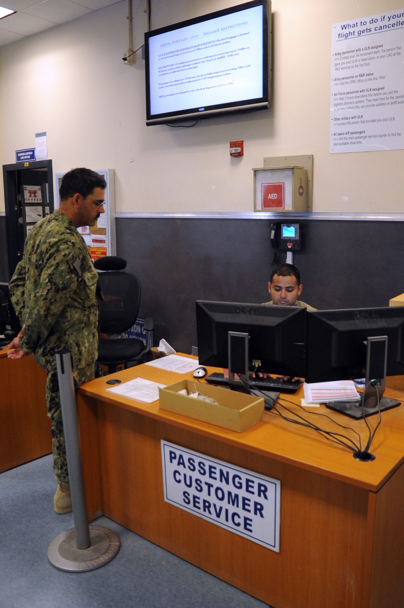 Staff Sgt. David Ramos, 455th Expeditionary Aerial Port Squadron passenger service agent, helps a customer at the passenger terminal on Bagram Airfield, Afghanistan, April 19, 2013. The 455th EAPS recently installed a customer service desk in the terminal to aid passengers who have general questions about flights. (U.S. Air Force photo/Staff Sgt. David Dobrydney)