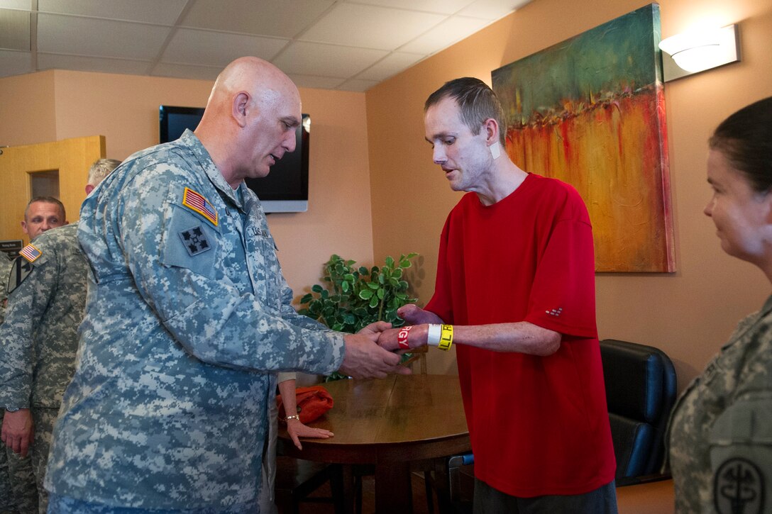 Army Chief of Staff Gen. Ray Odierno, presents challenge coin to Army Sgt. 1st Class Christopher Edwards during his visit to the Institute of Surgical Research burn unit on Joint Base San Antonio-Fort Sam Houston, Texas, April 16, 2013.