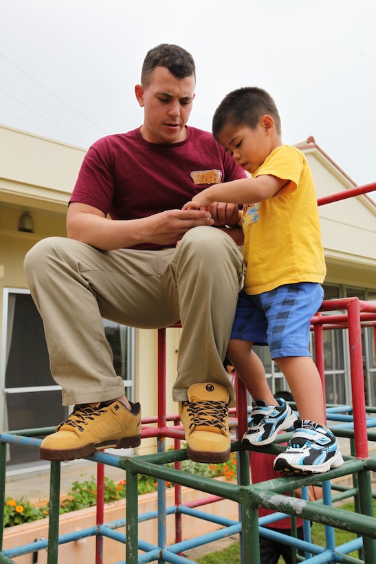 Corporal Steven V. Stroud, a metalworker for Combat Logistics Battalion 31, 31st Marine Expeditionary Unit, and native of Turlock, Calif., plays atop a jungle gym with a Japanese child during a visit here, April 20. Twenty-one service members and some family members donated part of their Saturday to play with local orphans, and provide an American-style barbecue of cheeseburgers and hot dogs. The Marines and Sailors of the 31st MEU are dedicated to matching their excellence in expeditionary capabilities with excellence as members of the Okinawan community.