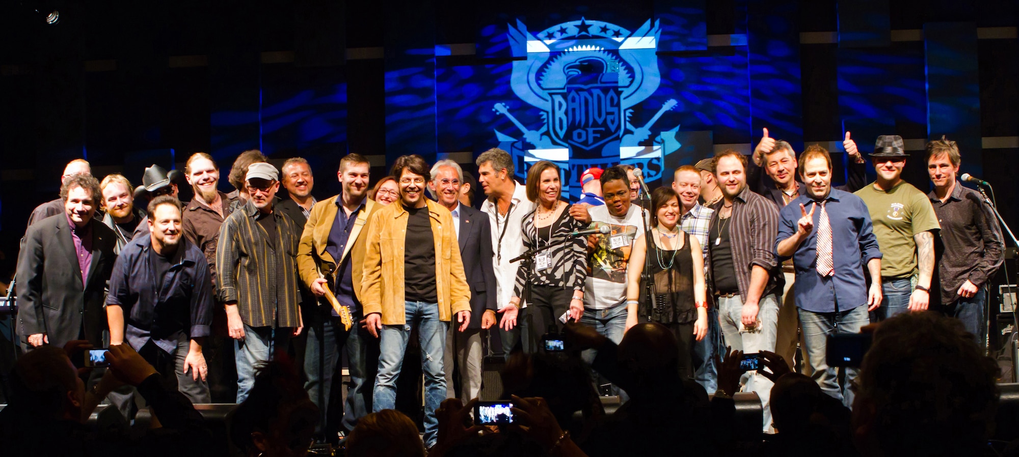 Tech. Sgt. Brian McNally, a guitarist for the Air National Guard Band of the Mid-Atlantic (front row, fourth from the left) stands with fellow veteran band mates of Bands of Brothers TV at the Bands of Brothers benefit concert, Nov. 12, 2012 at World Café Live, Philadelphia. The benefit concert was the finale show for 12 veterans who were brought together to form three bands that were filmed as part of a 10-episode online reality TV series. Bands of Brothers is a nonprofit organization that raises money for research and treatment in a dedicated effort of shedding light on post-traumatic stress disorder (Photo by Gene Thorpe Photography).