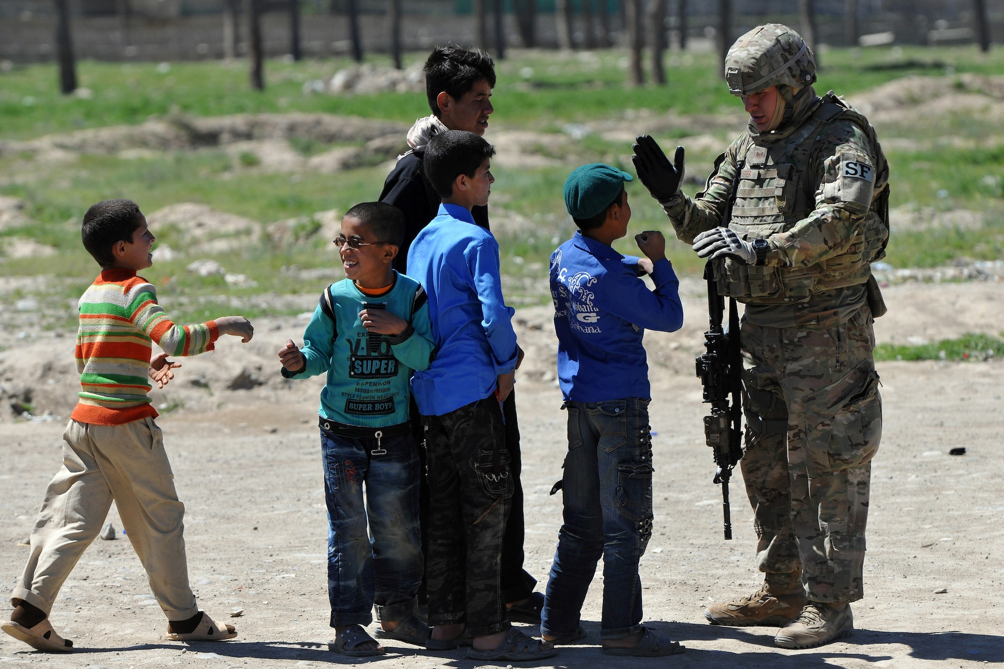 Staff Sgt. Michael Foster, 455th Expeditionary Security Forces Squadron entry control point NCOIC, meets with local Afghan children outside of Bagram Airfield, Afghanistan, April 16, 2013.  The 455th ESFS teams patrol the base perimeter looking for suspicious activities while local Afghan civilians arrive to receive basic medical care.  (U.S. Air Force photo/Senior Airman Chris Willis)