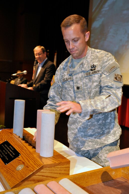 Lt. Col. James A. DeLapp, U.S. Army Corps of Engineers Nashville District commander, places a piece of a scale pile model cast of the Foundation Remediation Concrete pile that was cast from final barrier wall concrete placement on March 6, 2013 at a Completion Ceremony of rehabilitation work for the Wolf Creek at the Russell County schools Auditorium/Natatorium, April 19, 2013.  The Wolf Creek Dam remediation project is considered a model project and the largest project of its kind in the world.
