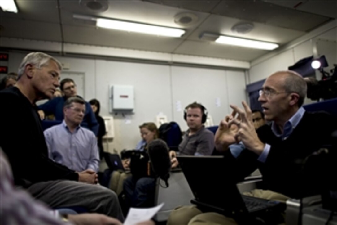 U.S. Defense Secretary Chuck Hagel, left, listens to a question from Dan DeLuce, a reporter for Agence France-Presse, during a news briefing en route to Israel, April 20, 2013. Hagel is starting a six-day trip to the Middle East, where he will visit foreign counterparts. 