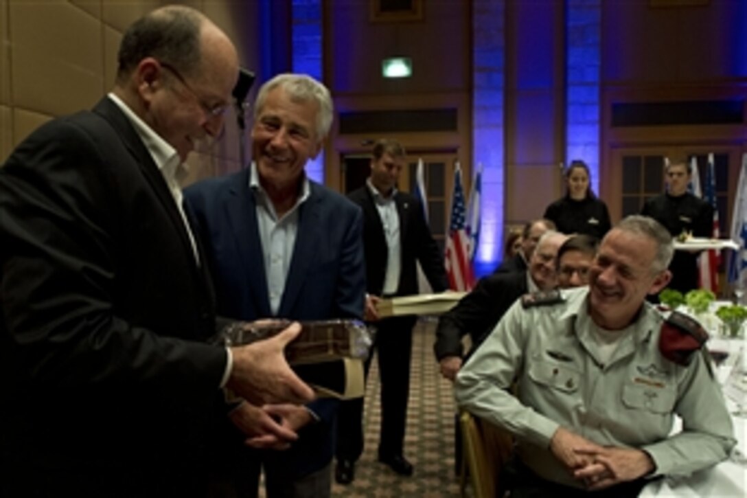 U.S. Defense Secretary Chuck Hagel, center, shares a laugh with Israeli Defense Minister Moshe Yaalon after being presented with a Bible written in Hebrew following an official dinner in Jerusalem, April 21, 2013. 