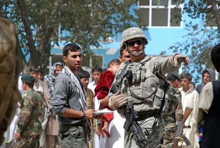 Captain Joseph Merrill from Binghamton, NY and commander of SECFOR Delta works with a translator to direct a father seeking medical attention for his son.