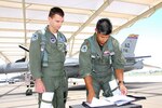First Lt. Adam Jantas (left), a Polish Air Force student pilot, goes over his morning sortie with F-16 instructor pilot Maj. Julian Pacheco on the 162nd Fighter Wing flightline.