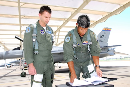 First Lt. Adam Jantas (left), a Polish Air Force student pilot, goes over his morning sortie with F-16 instructor pilot Maj. Julian Pacheco on the 162nd Fighter Wing flightline.