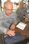 Chief Warrant Officer Tom Marsh (left) and 1st Sgt. Kyle Heidenreich work on a preliminary deployment kit during a Logistics Enablers Overview Course Aug. 15 in Bismarck, N.D. Marsh uses the laptop to write information to the green tag, which will track equipment. The kit is one of several pieces of equipment covered during the weeklong course that included Soldiers from across the United States.