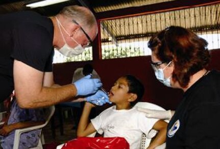 Lt. Col. (Dr.) Philip Bales gives 8-year-old Pedro Mayen an injection before extracting a tooth while Tech. Sgt. Rose Hartzell comforts the boy Aug. 18 in Santa Rosa, Guatemala. Colonel Bales is assigned to the 173d Medical Group of the Oregon National Guard, and Sergeant Hartzell is a 163rd Medical Group dental technician from the California Air National Guard.