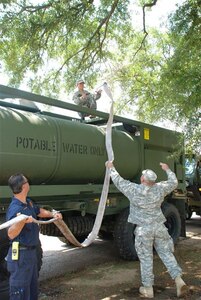 Army Sgt. Michael Slayter of Winnfield, La., tosses a hose to Army Spc. Joseph P. Gauthier of Natchitoches, La. The Louisiana National Guard soldiers are members of Detachment 1, A Company, 199th Leadership Brigade Support Battalion, 256th Infantry Brigade Combat Team, in Colfax, La.