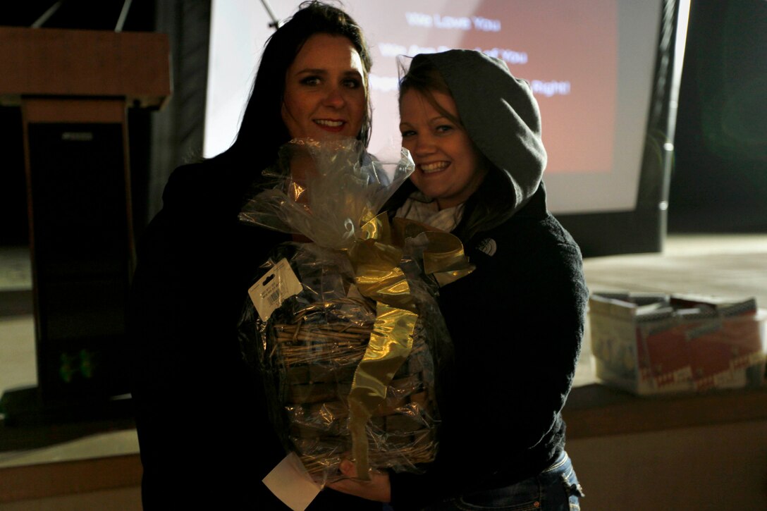 Kristine Schellhaas, left, presents Emily Sollars, right, with a gift basket from the raffle during the Live, Laugh and Learn event at the Del Mar Beach Resort here April 19. The tour features motivational presentations, book signing and author meet-and-greet events for military wives. Schellhaas is the 2013 Camp Pendleton Military Spouse of the Year, founder of USMC Life and co-host of Semper Feisty Radio.

