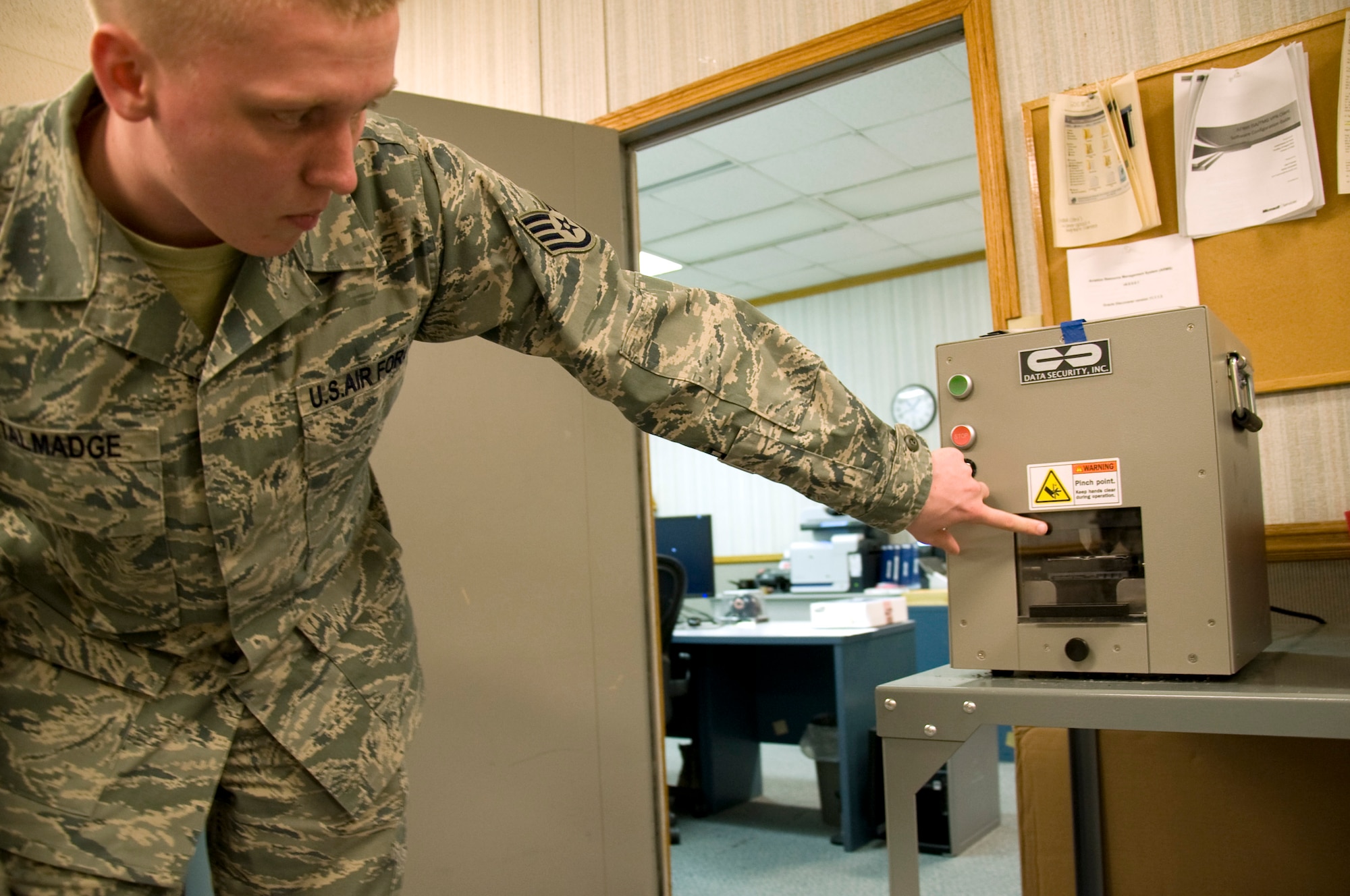 Staff Sgt. Brandon Talmadge, 436th Communications Squadron NCO in charge of client systems, explains how the crusher breaks hard drives using a pressure from a bar April 16, 2013, at Dover Air Force Base, Del. Talmadge ships hard drives and other computer parts to Defense Logistics Agency Disposal Disposition Services to be recycled for parts and to be used in other computers.(U.S. Air Force photo/Senior Airman Jared Duhon)