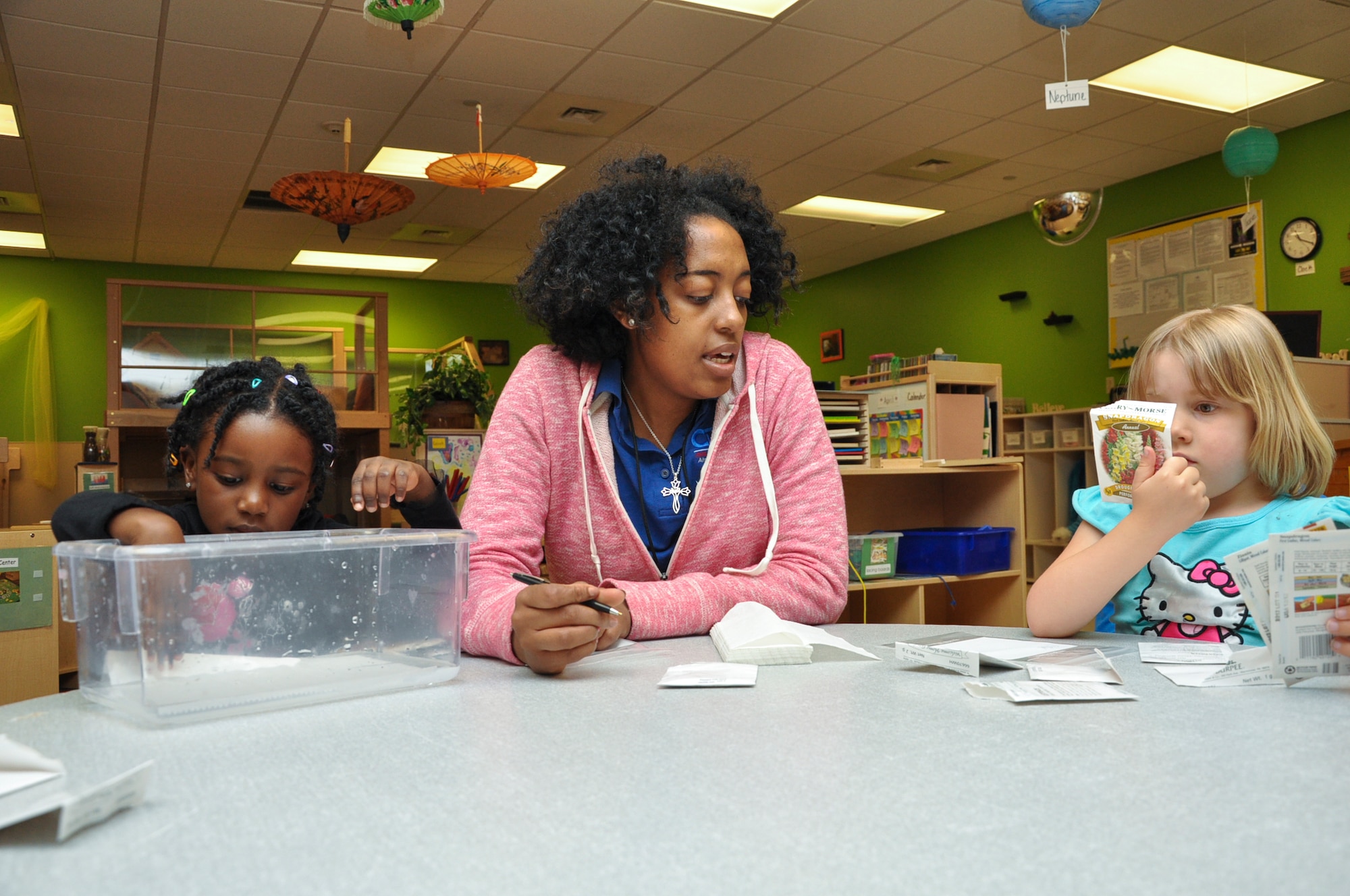 Maryon Bradshaw, center, A-Basin Child Development Center preschool teacher, instructs students Jaelyn Wilson, left, and Chloe Jepperson on how to construct their seed germination project April 22, 2013 on Buckley Air Force Base, Colo. Children put several seeds into a moist paper towel, placed them into a bag and then hung them by a window. The project was done in observance of Earth Day. (U.S. Air Force photo by Staff Sgt. Christopher Gross/Released)