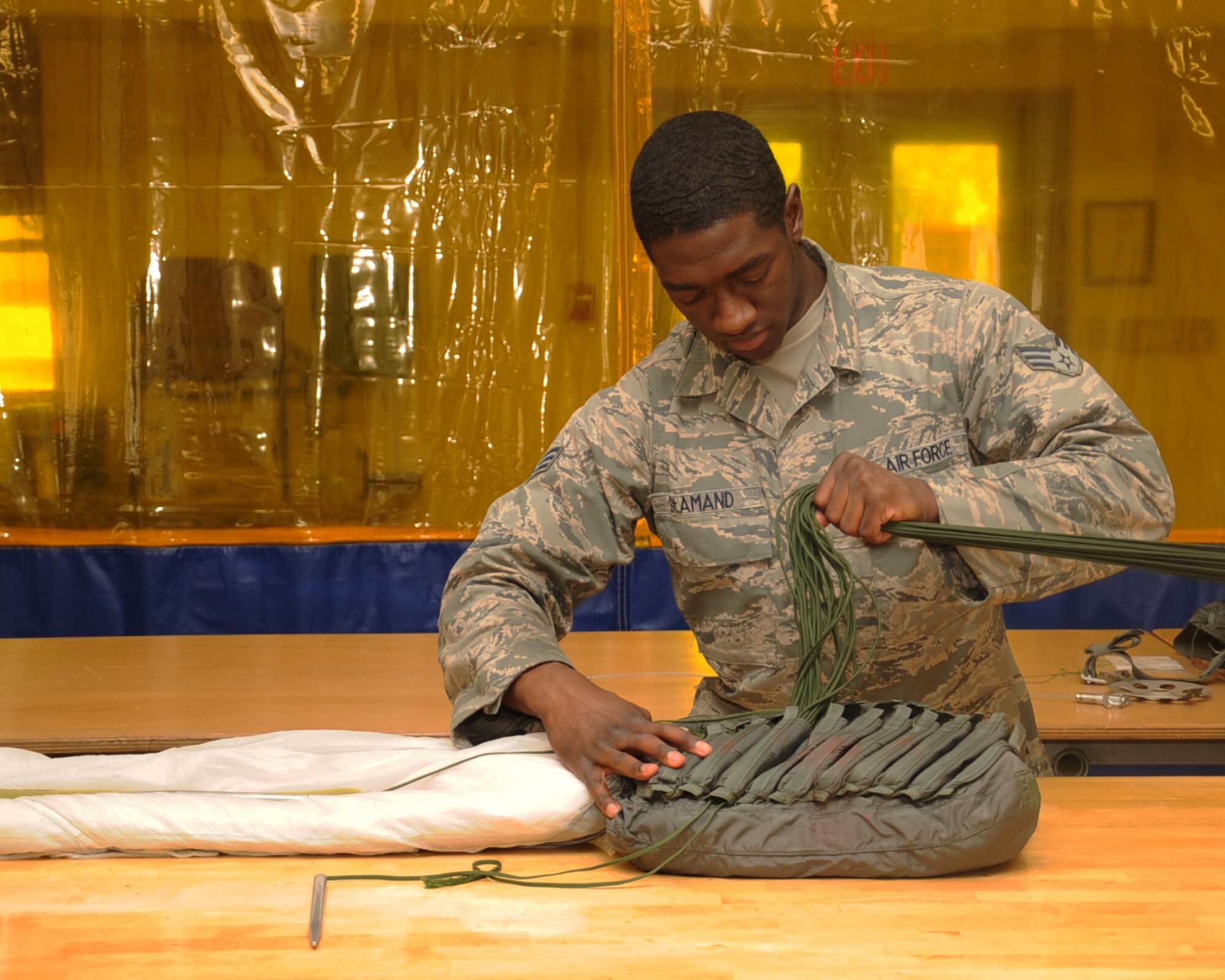 Senior Airman Ernest St. Amand, 2nd Operations Support Squadron Aircrew Flight Equipment, stows lines on a parachute on Barksdale Air Force Base, La., April 22, 2013. The AFE parachute shop is in charge of packing, inspecting, and supplying B-52H Stratofortress aircrew with parachutes. (U.S. Air Force photo/Senior Airman Sean Martin)