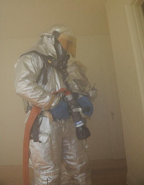 Kelly Cravens, foreground, and Senior Airman Trey Moorer, 2nd Civil Engineer Squadron firefighters, simulate extinguishing a fire during an exercise on Barksdale Air Force Base, La., April 20, 2013. The exercise put firefighters in a simulated house fire where they established water lines, practiced methods of entry and extinguished simulated fires. (U.S. Air Force photo/Airman 1st Class Andrew Moua)