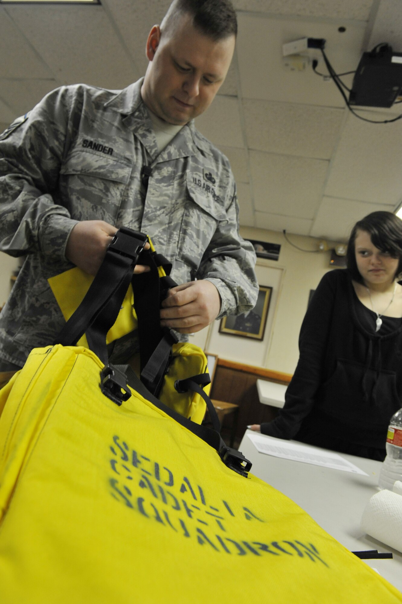 Master Sgt. William Sander, 509th Comptroller Squadron financial services superintendent, shows Cynthia, 14, how to properly prepare search and rescue equipment during a Civil Air Patrol meeting, March 28, 2013, in Sedalia, Mo. Students learn different skills to help them prepare for emergency communications and disaster relief. (U.S. Air Force photo by Heidi Hunt/Released)