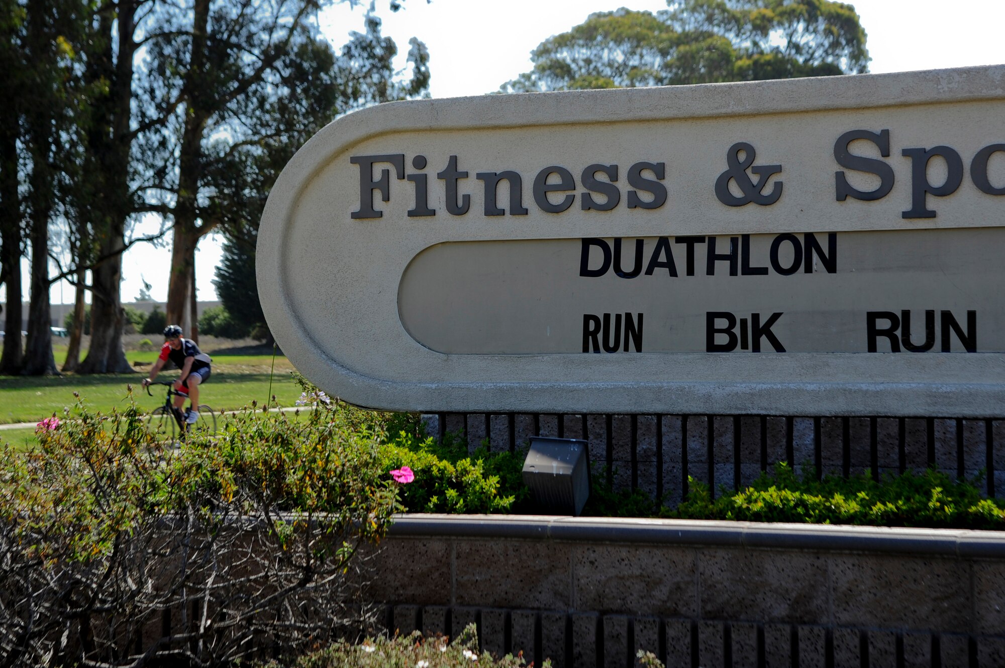 VANDENBERG AIR FORCE BASE, Calif. – A Team V member rides past a marquee sign outside of the Fitness and Sports Center during the last leg of the bicycle portion of a duathalon here Saturday, April 20, 2013. The duathalon, sponsored by the 30th Force Support Squadron, consisted of a 5 km run, a 12 km bike and a 5 km run. (U.S. Air Force photo/Senior Airman Lael Huss)