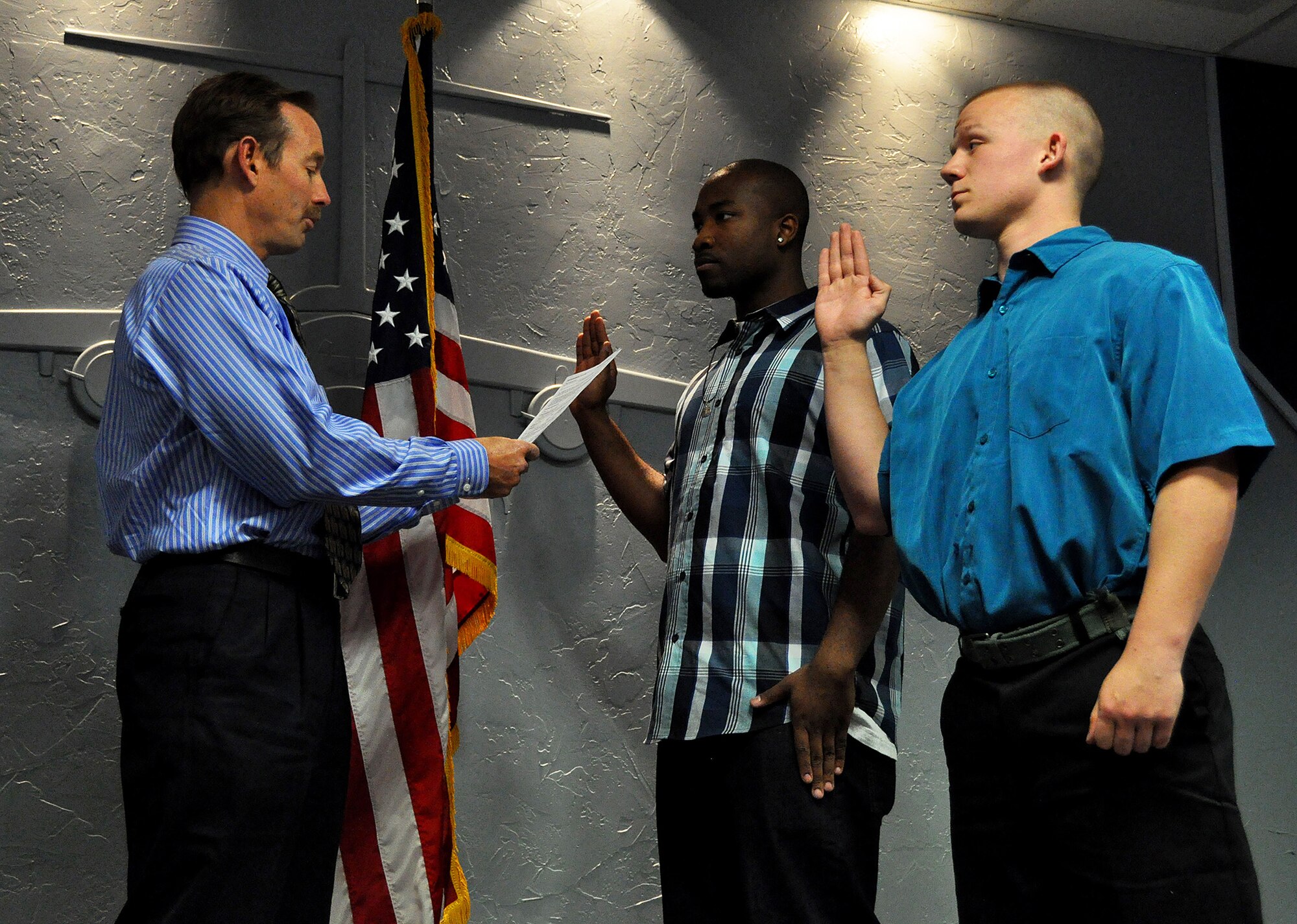 Rob Williamson, retired Air Force F-15 pilot, reads the oath of enlistment while DeAndre Threet (middle) and Zackery Robinson (right) repeat it at the 446th Airlift Wing headquarters here April 19. Williamson, who served six years active duty and 17 years in the Reserve, met Threet 10 years ago through the Big Brothers Big Sisters of America program. Now, Threet has made the decision to serve in the Air Force himself and will be joining the 446th Security Forces Squadron after completing basic training and technical school. (U.S. Air Force photo by Airman 1st Class Madelyn McCullough)