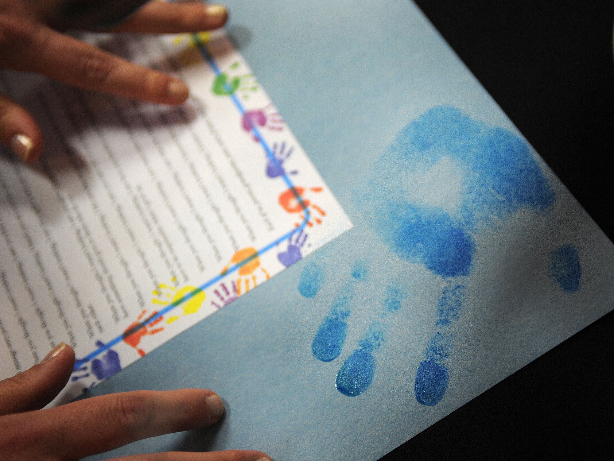A child makes a hand print on a flyer at the inaugural Cannon Helping Hands celebration at Cannon Air Force Base, N.M., April 19, 2013. Helping Hands was held to bring awareness about base programs available for military families. (U.S. Air Force photo/Airman 1st Class Ericka Engblom)