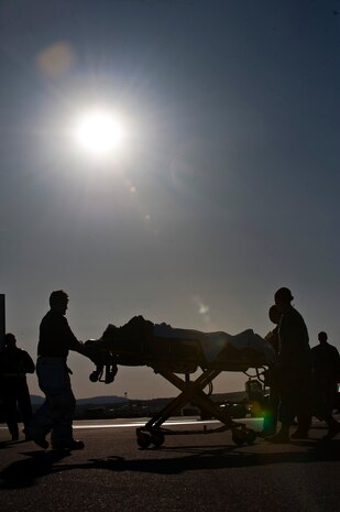 Medical Airmen from the 99th Aerospace Medical Squadron transport a simulated victim on a stretcher during an exercise at the hot cargo pad April 18, 2013, on the Nellis Air Force Base, Nev., flightline. The 99th Air Base Wing Plans and Programs Office coordinates and conducts a variety of exercises throughout the year in order to test Nellis’ ability to respond to potential real world situations. (U.S. Air Force photo/Senior Airman Brett Clashman)