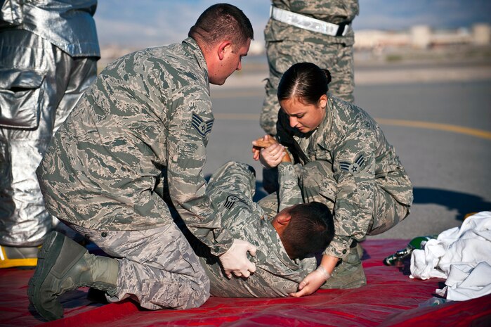 Staff Sgt. Ryan Stafford (left), and Senior Airman Gloria Jasso (right), 99th Aerospace Medical Squadron flight medical technicians, assist Staff Sgt. Charles Carter, 624th AMDS medical technician, during an exercise April 18, 2013, at the hot cargo pad  on the Nellis Air Force Base, Nev., flightline. The exercise tested Nellis servicemembers to include 99th Civil Engineer Squadron’s firefighters and bioenvironmental Airmen, 99th Security Forces Squadron and 99th AMDS’s medical personnel on their ability to act as first responders to a major munitions mishap. (U.S. Air Force photo/Senior Airman Brett Clashman)  