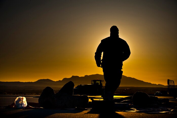 Sean Conley, 99th Civil Engineer Squadron fire department driver operator, runs to check the status of simulated victims during a ground mishap exercise April 18, 2013, on the hot cargo pad on the Nellis Air Force Base, Nev., flightline. Nellis Airmen participated in a simulated scenario to test their accident response readiness. (U.S. Air Force photo/Senior Airman Brett Clashman)