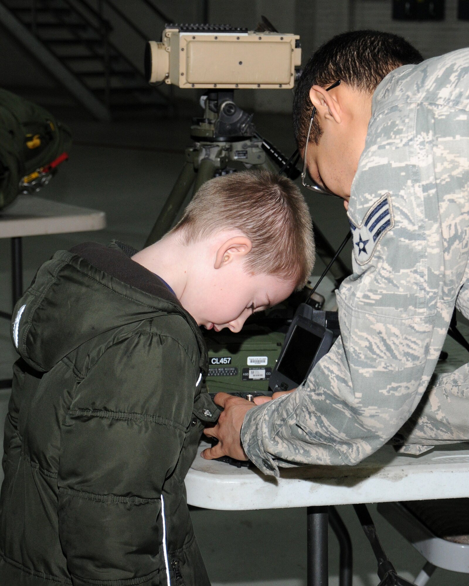 Senior Airman Bruce Wade, 321st Special Tactics Squadron transmission system journeyman from Ridgecrest, Calif., shows Aidan King, 7, son of Master Sgt. Virginia King, 352nd Special Operations Group Manpower and Organization NCO in charge, an assault zone light used for marking landing strips April 19, 2013, at RAF Mildenhall, England. As part of Job Shadow Day, children received hands-on experience of handling equipment used by Service members. (U.S. Air Force photo by Gina Randall/Released)
