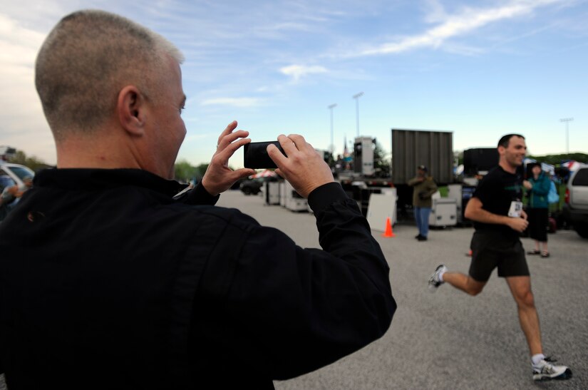 A man takes a photo of a runner seconds before he crosses the finish line of the Joint Base Andrews Half Marathon, April 13, 2013. A half marathon is 13.1 miles. (U.S. Air Force photo/Staff Sgt. Brittany E. Jones)