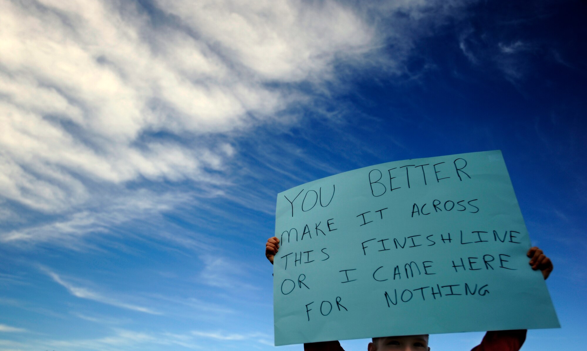 A child of a half marathon participant holds a sign near the finish line April 13, 2013 at Joint Base Andrews, Md. The child's mother was participating in her first half marathon. (U.S. Air Force photo/Staff Sgt. Brittany E. Jones)