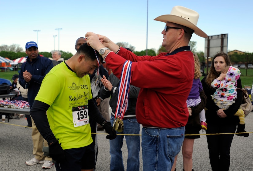 A runner receives a medal after crossing the finish line April 13, 2013 at Joint Base Andrews, Md. Medals were handed out to all participants of the Joint Base Andrews Half Marathon. (U.S. Air Force photo/Staff Sgt. Brittany E. Jones)