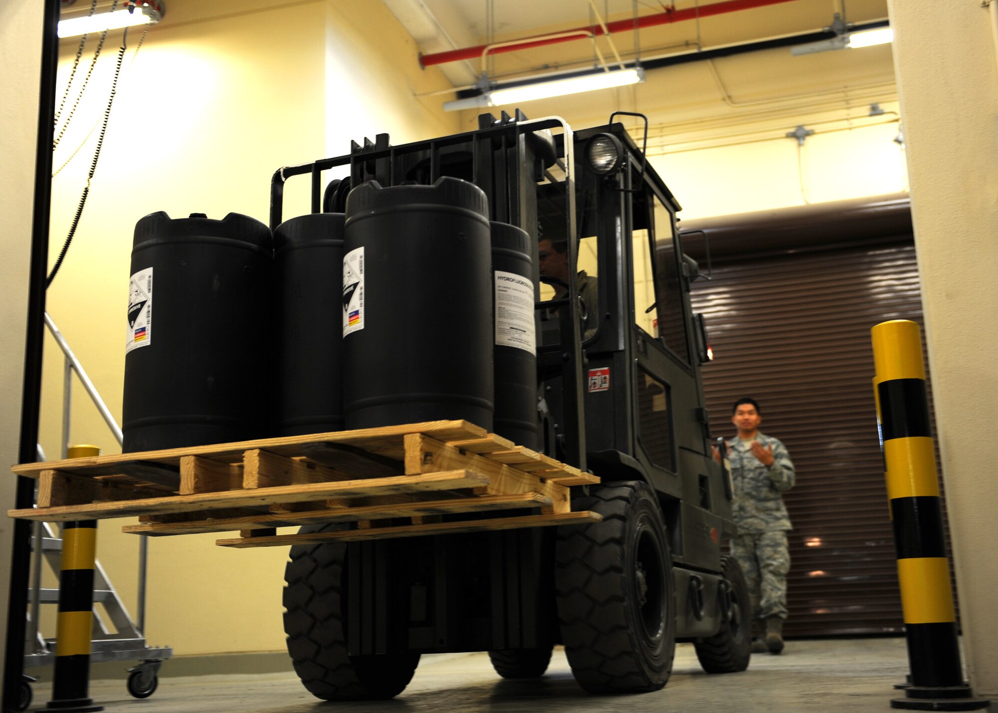 Airman 1st Class Michael Brown, 39th Logistics Readiness Squadron hazardous materials pharmacy technician, moves a pallet of hydrofluoric acid with a forklift as Senior Airman Marques Barcelona, 39th LGRS HAZMART pharmacy technician spots the movement at Incirlik Air Base, Turkey April 18, 2013. HAZMART pharmacy technicians operate a specially designed and equipped warehouse to maintain the base’s hazardous material supplies. (U.S. Air Force photo by Senior Airman Chase Hedrick/Released)