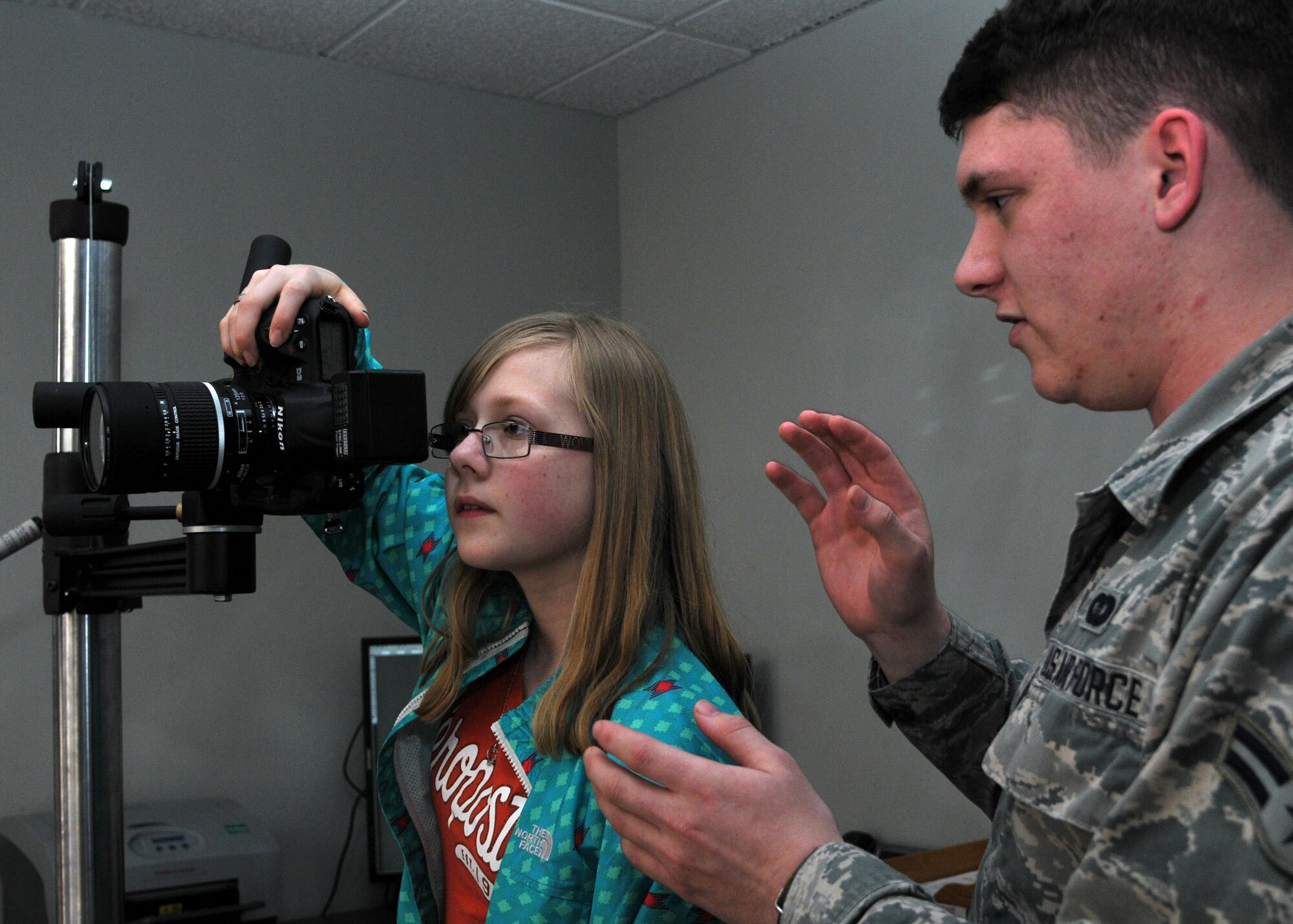 From right, Airman 1st Class Dillon Johnston, 100th Air Refueling Wing Public Affairs photojournalist from Alameda, Calif., explains how to take a studio photo to Rebecca Grillo, 14, daughter of Master Sgt. Penny Humphrey, 100th Force Support Squadron Manpower and Organization NCO in charge from Mt. Vernon S.D., during Job Shadow Day April 19, 2013, at RAF Mildenhall, England. Students visiting public affairs were shown in ins-and-outs of photography as week as broadcasting. (U.S. Air Force photo by Airman 1st Class Kelsey Waters/Released)