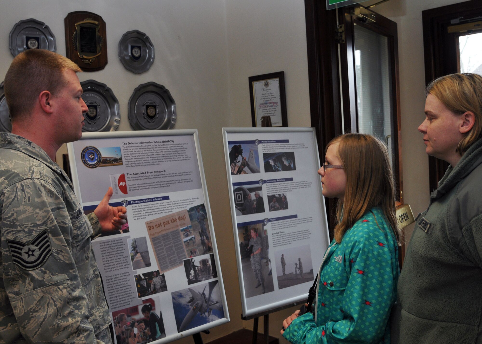 From left, Tech. Sgt. Neal Joiner, 100th Air Refueling Wing Public Affairs community relations NCO in charge from Marble Hill, Mo., explains the Public Affairs mission to Rebecca Grillo, 14, and her mother Master Sgt. Penny Humphrey, 100th Force Support Squadron Manpower and Organization NCO in charge from Mt. Vernon S.D., during Job Shadow Day April 19, 2013, at RAF Mildenhall, England. Students visiting public affairs received hands-on experience with photography equipment and discussed videography, journalism and social media. (U.S. Air Force photo by Airman 1st Class Kelsey Waters/Released)