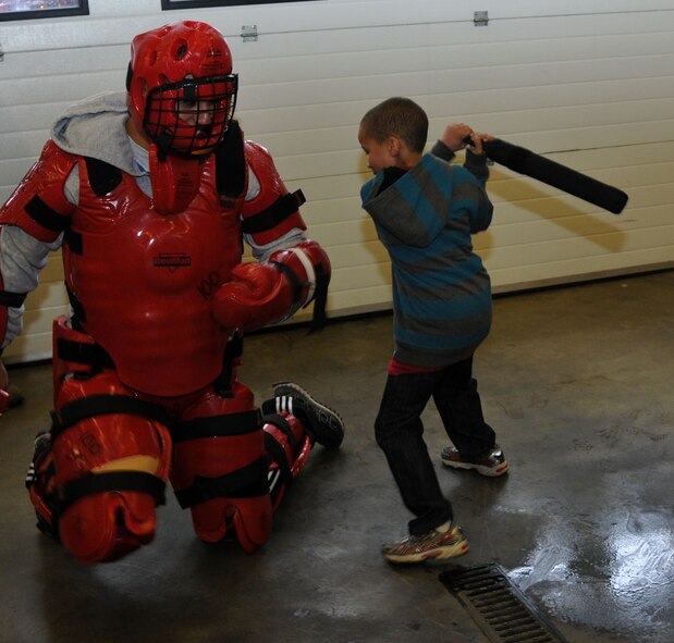 Tyler Thompson, 8, son of Moses Thompson, 100th Force Support Squadron deputy director, practices baton techniques on a service member of the 100th Security Forces Squadron during Job Shadow Day April 19, 2013, on RAF Mildenhall, England. Job Shadow Day had many different displays at various squadrons including security forces, logistics readiness and civil engineer. (U.S. Air Force photo by Airman 1st Class Kelsey Waters/Released)