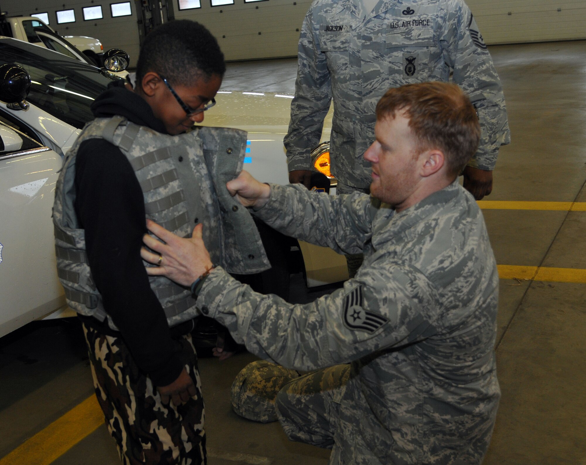 Staff Sgt. Charles Nelson, 100th Security Forces Squadron NCO of supply from Rossville, Ga., helps Caiden Green, 8, son of Joe Dale, 100th Communications Squadron telecommunications specialist from Vacaville, Calif., try on Interceptor Body Armor April 19, 2013, at RAF Mildenhall, England. Job Shadow Day has been going on for over five years and is an educational way for children to learn about the different carriers offered by the U.S. Air Force. (U.S. Air Force photo by Airman 1st Class Kelsey Waters/Released)