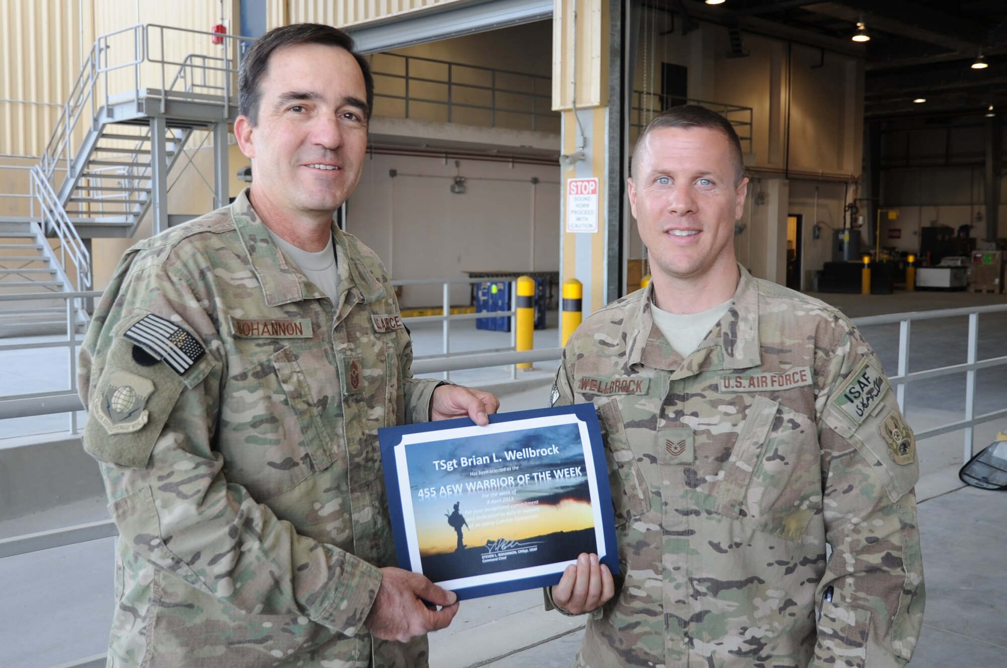Chief Master Sgt. Steve Bohannon, Command Chief Master Sergeant of the 455th Air Expeditionary Wing, presents the "Warrior of the Week" award to Tech. Sgt. Brian Wellbrock, 455th Expeditionary Aerial Port Squadron NCO in charge of short take-off and landing flights, April 17, 2013, on Bagram Airfield, Afghanistan. Wellbrock is responsible for the $88 million STOLs contract and coordinated delivery of 7,000 pieces of mail and 30 pallets of food to remotely deployed servicemembers. (U.S. Air Force photo/Staff Sgt. David Dobrydney)